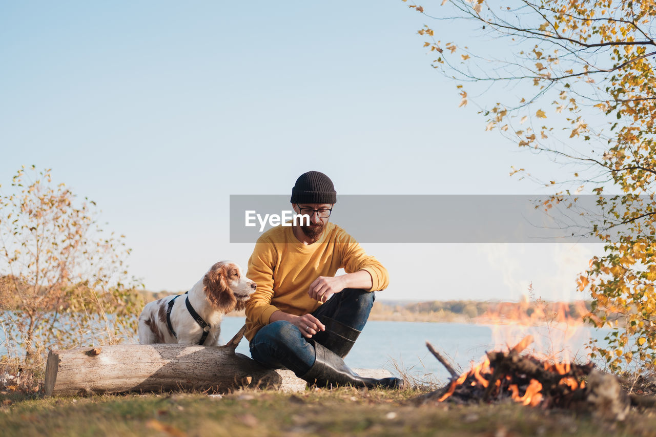 Man with dog sitting against sky