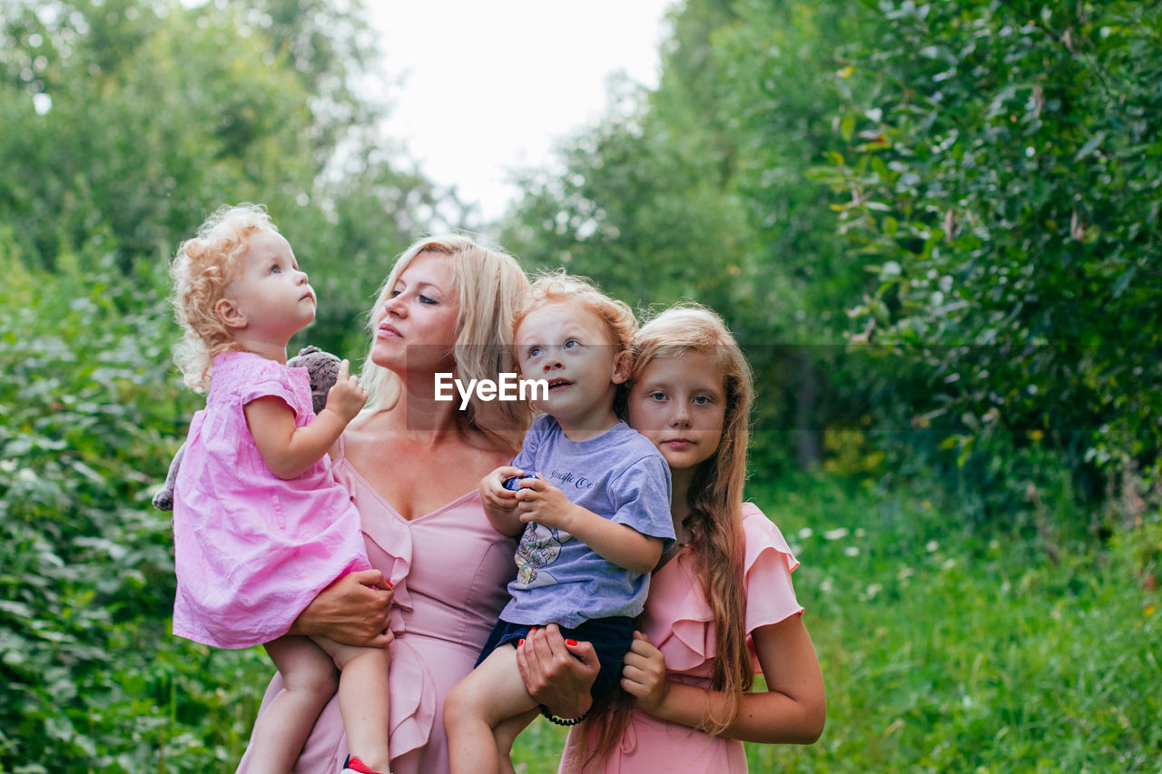 Portrait of a mom with two daughters and son standing against plants