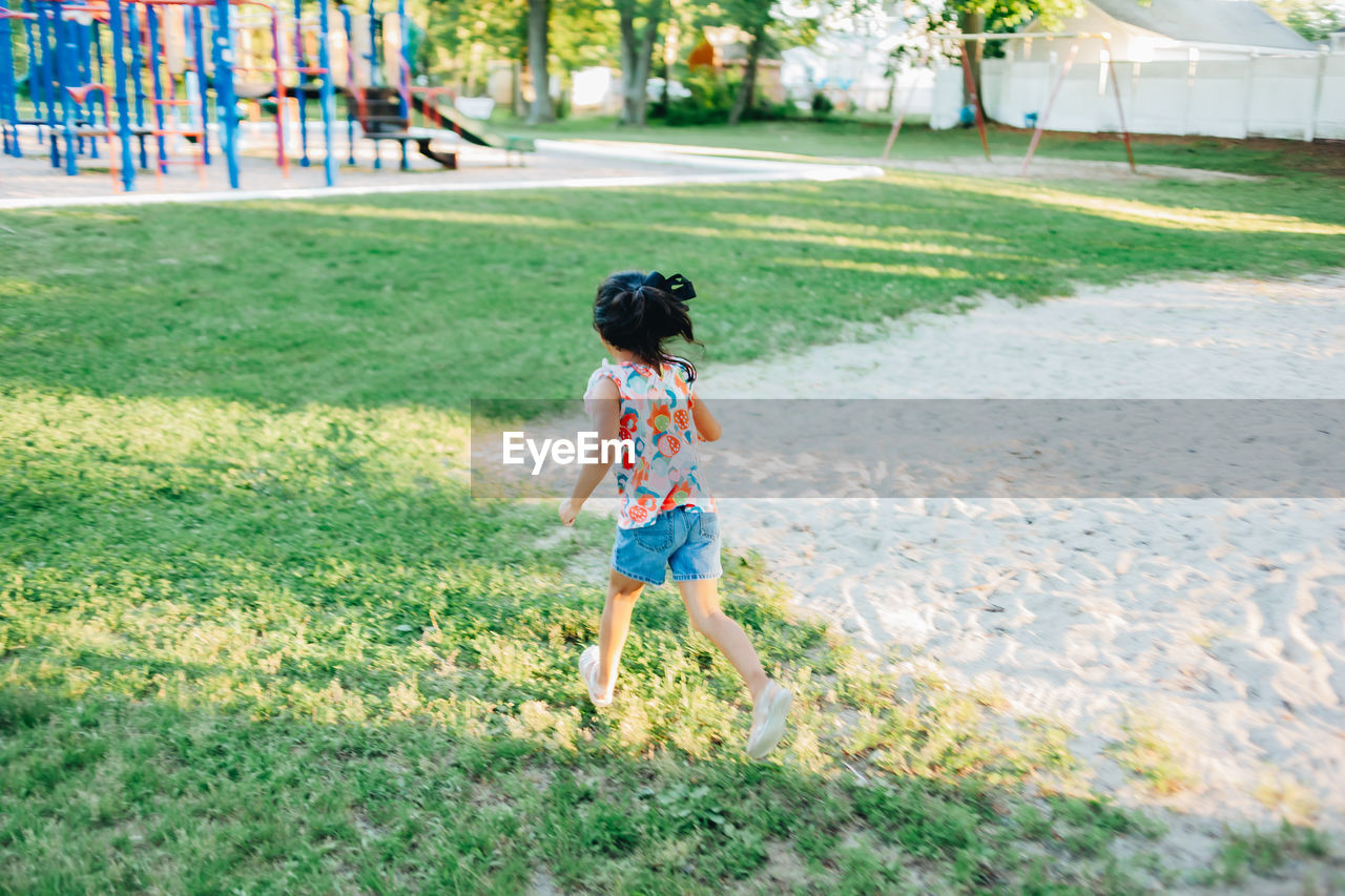 Diverse mixed race pre school girl outdoors during summer having fun at playground park 