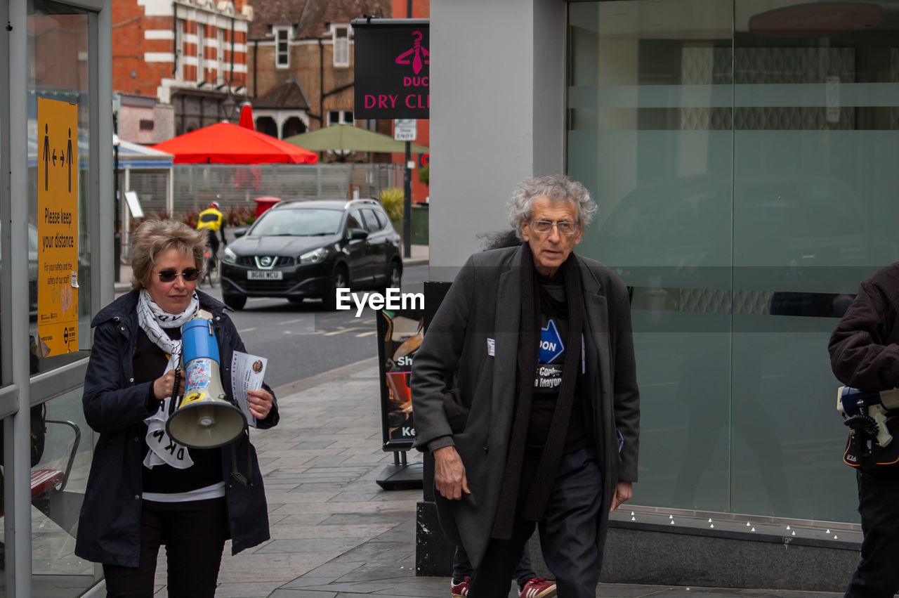 FULL LENGTH OF MAN WALKING ON STREET IN CITY