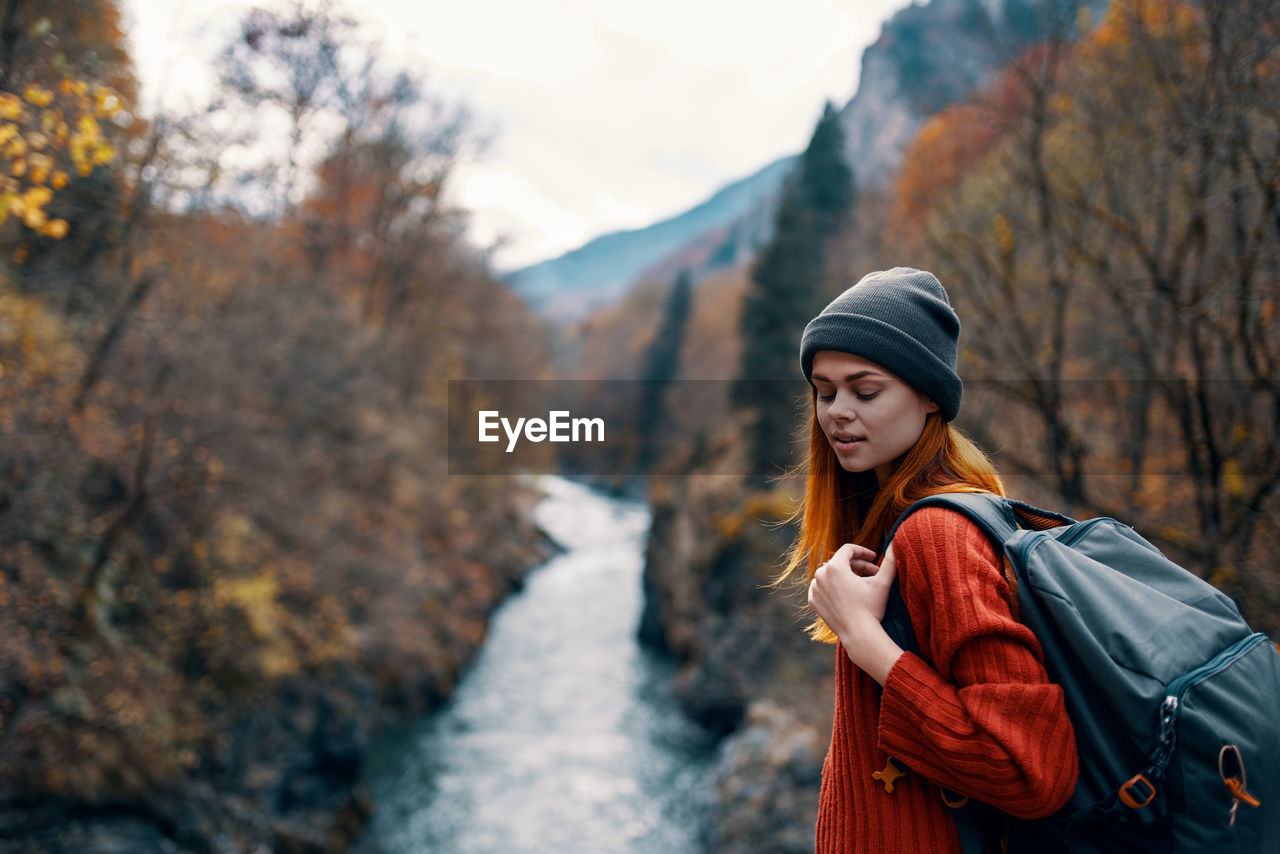 WOMAN STANDING BY TREE IN MOUNTAINS