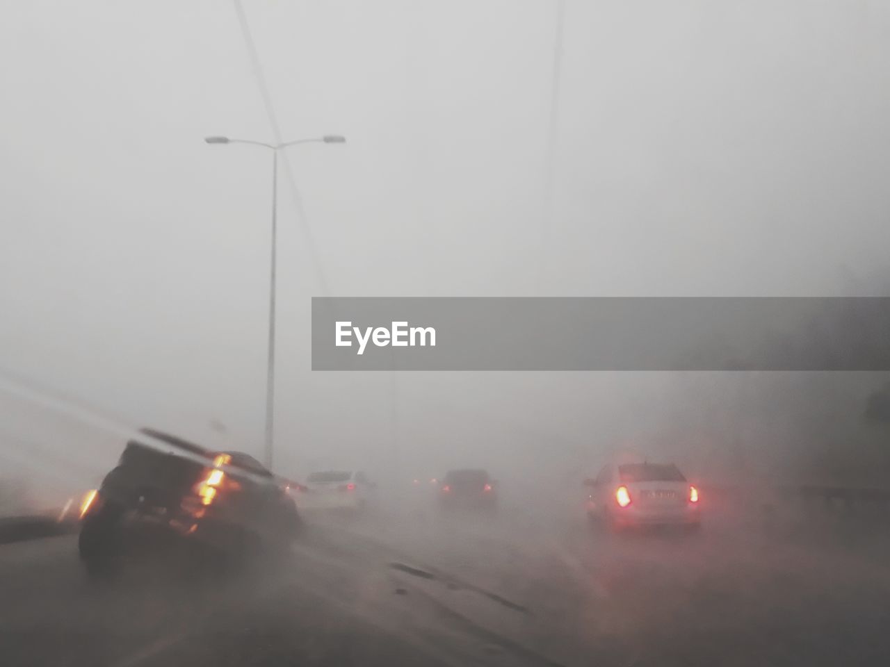 CARS ON ROAD DURING RAINY SEASON AGAINST SKY