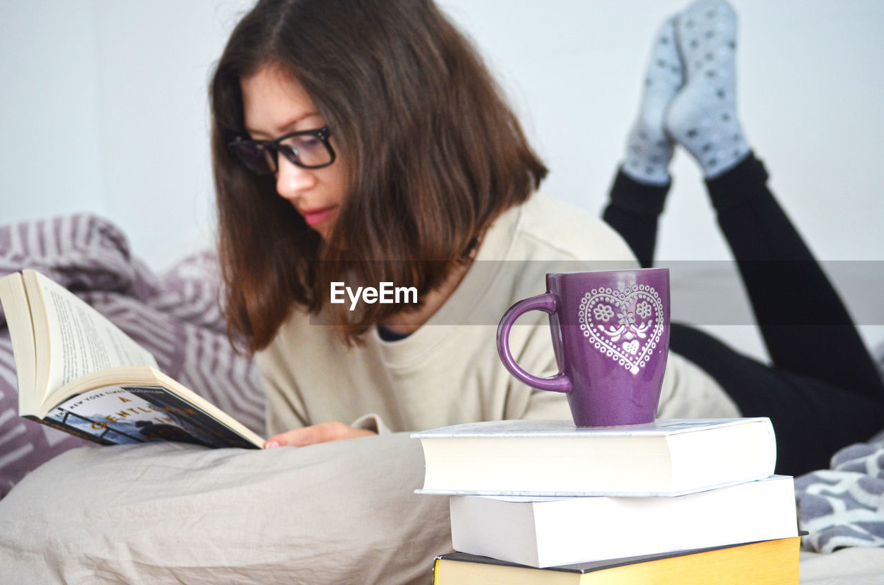 YOUNG WOMAN SITTING ON BOOK WITH EYEGLASSES
