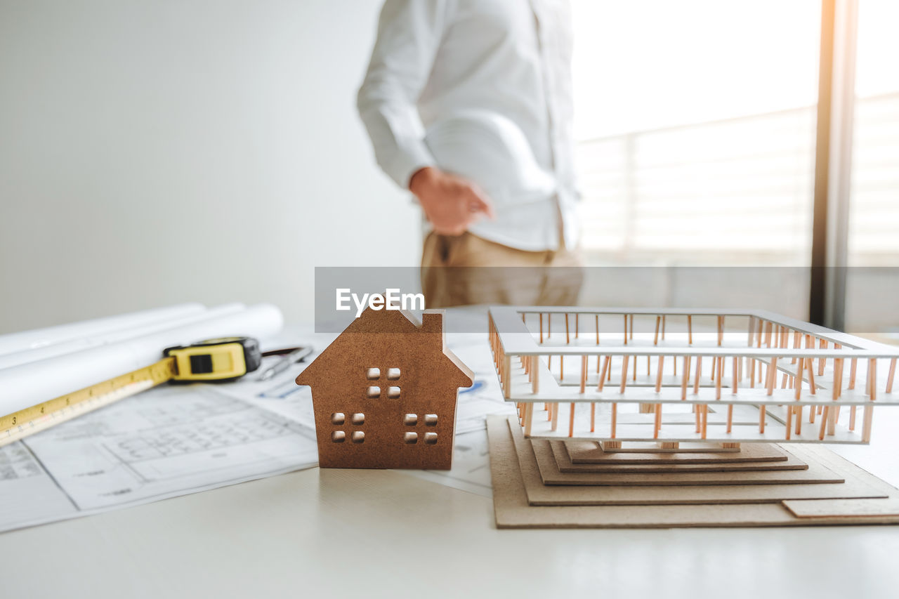 MIDSECTION OF MAN HOLDING PAPER WHILE STANDING AT HOME