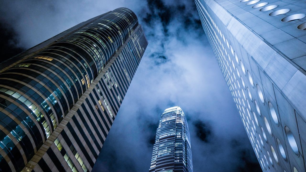 Low angle view of modern buildings against cloudy sky at night