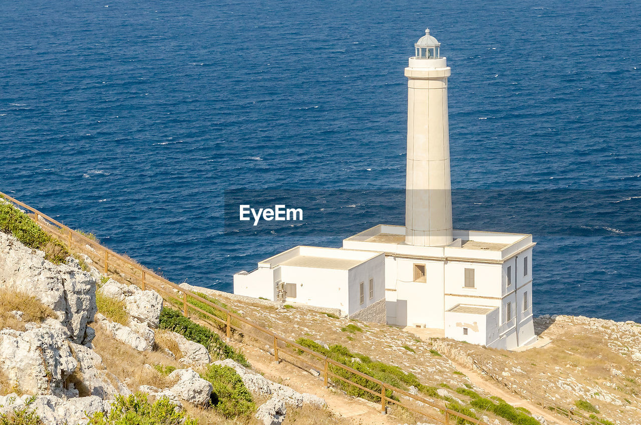 High angle view of lighthouse by sea against buildings