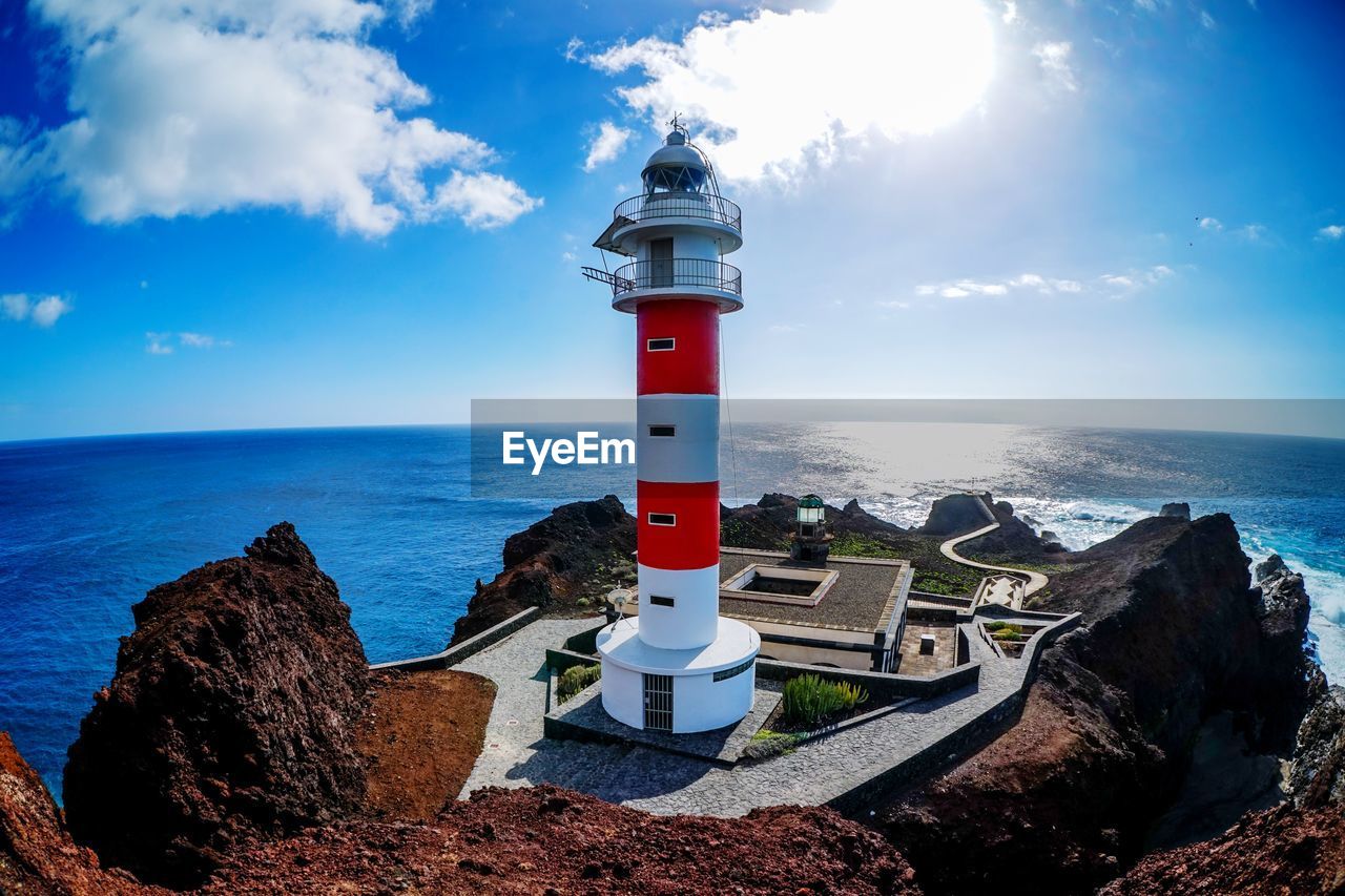 Lighthouse by sea against sky