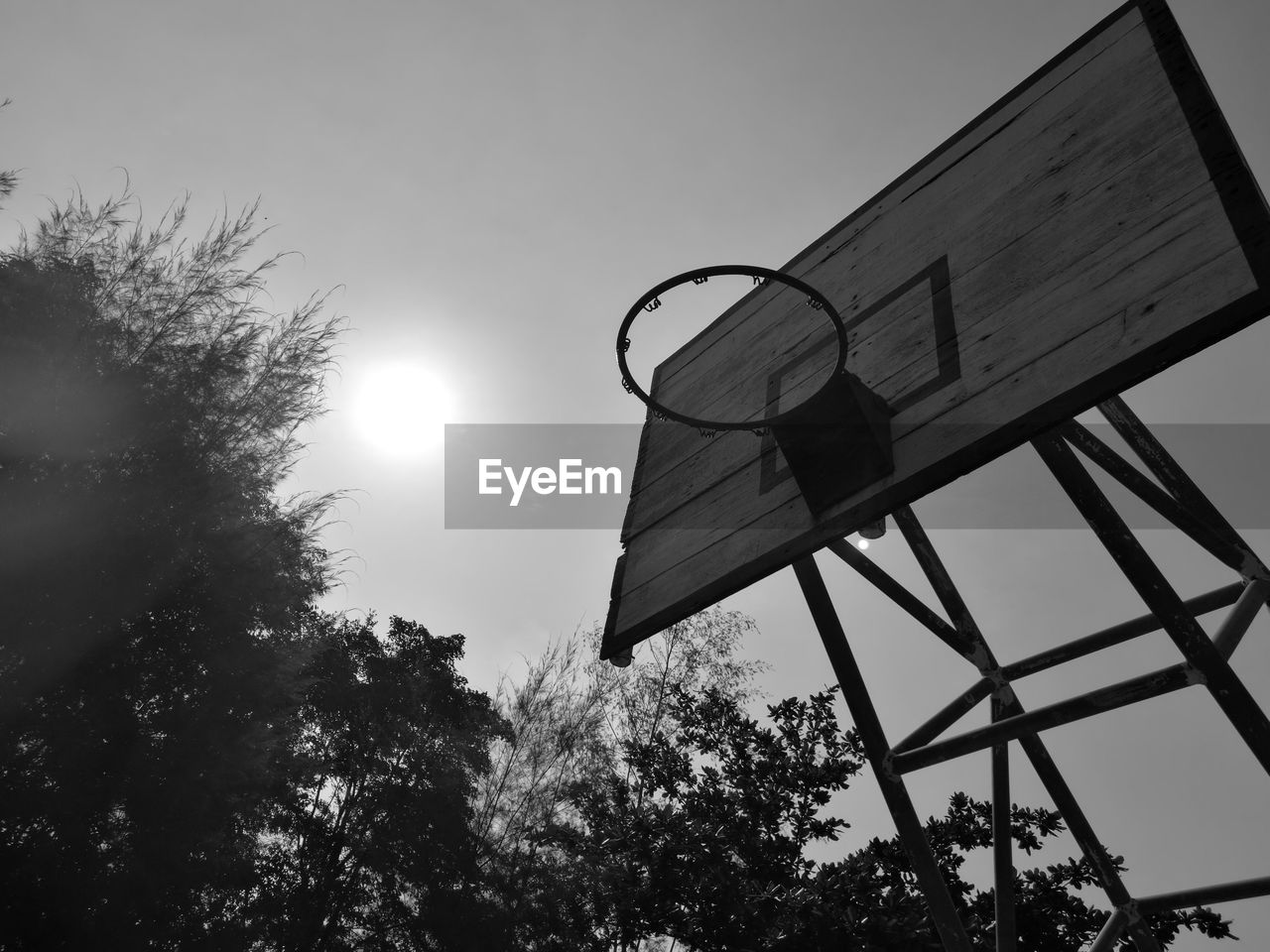 LOW ANGLE VIEW OF BASKETBALL HOOP AT SUNSET