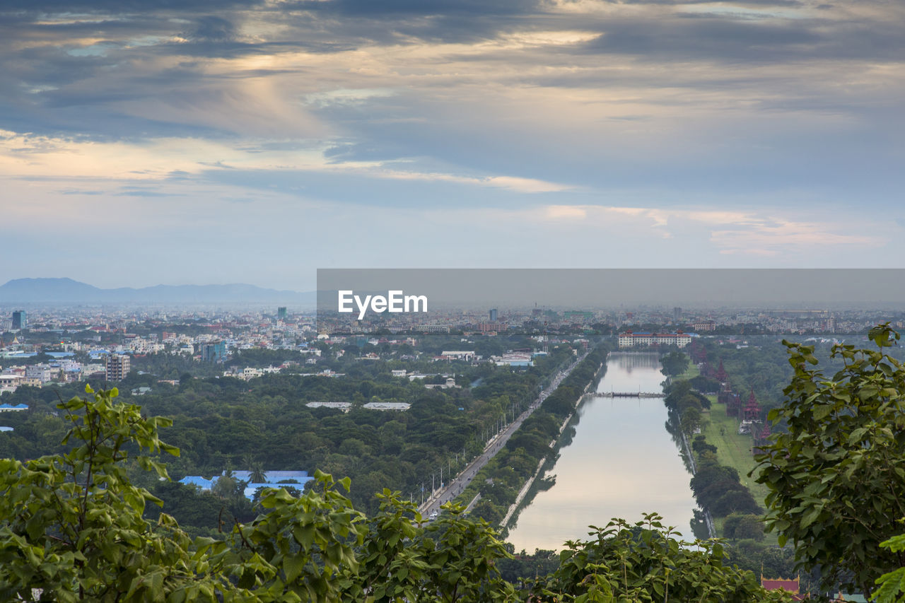 HIGH ANGLE VIEW OF BUILDINGS AND RIVER AGAINST SKY