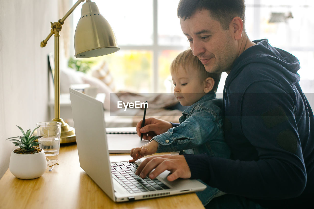 Side view of man using laptop at home