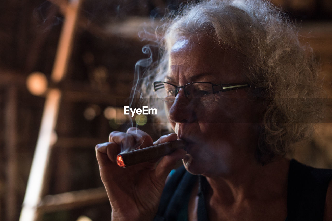 Close-up portrait of a old woman smoking cigar