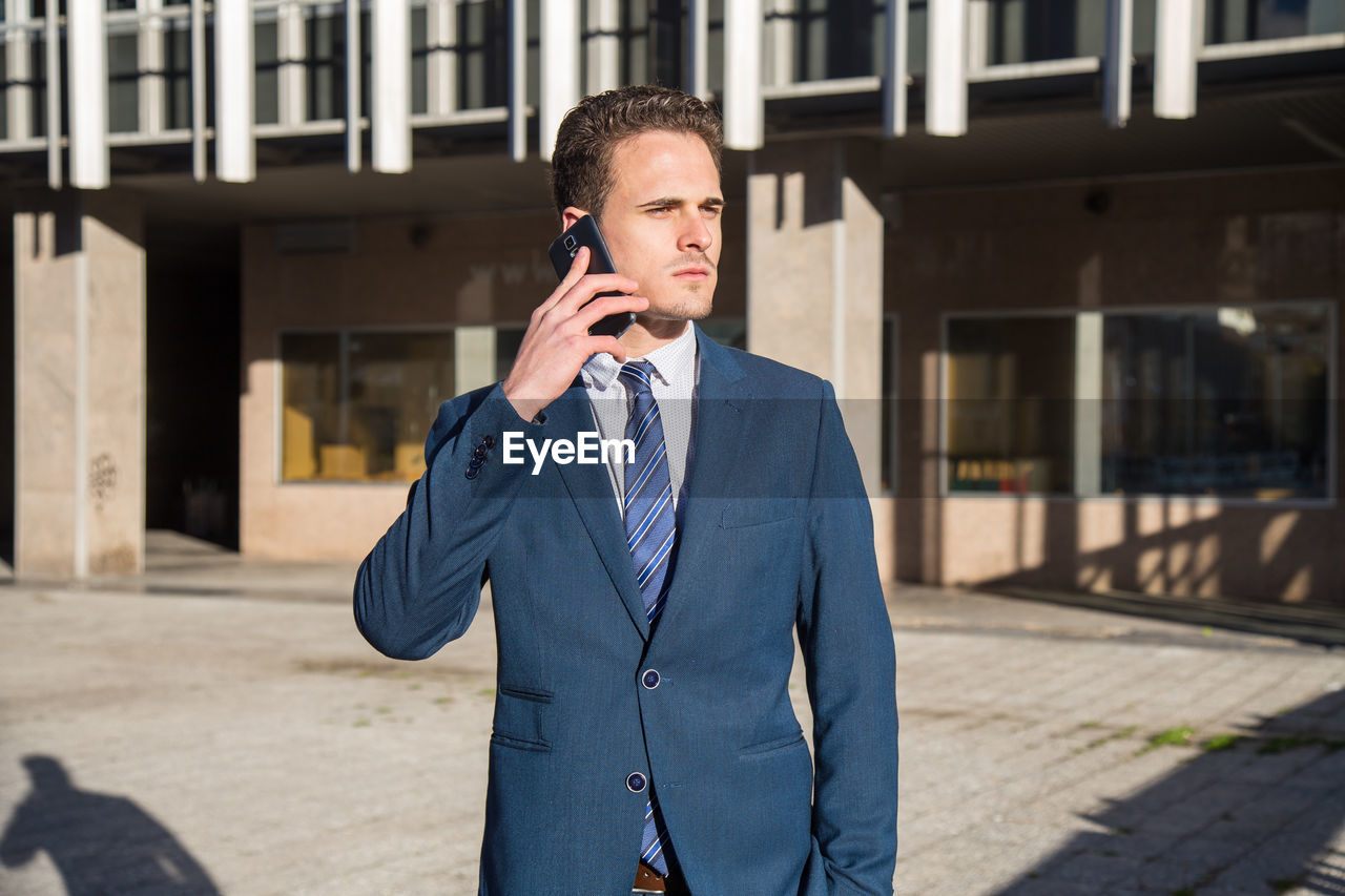 Businessman talking on phone while standing in city