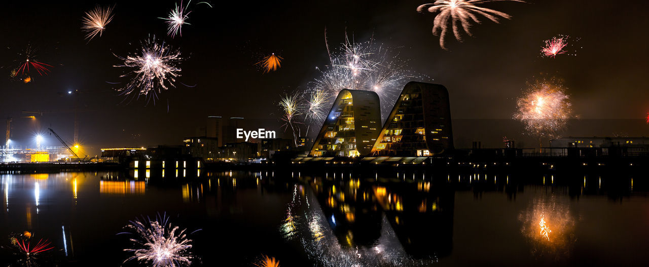 Reflection of illuminated buildings and fireworks in river at vejle
