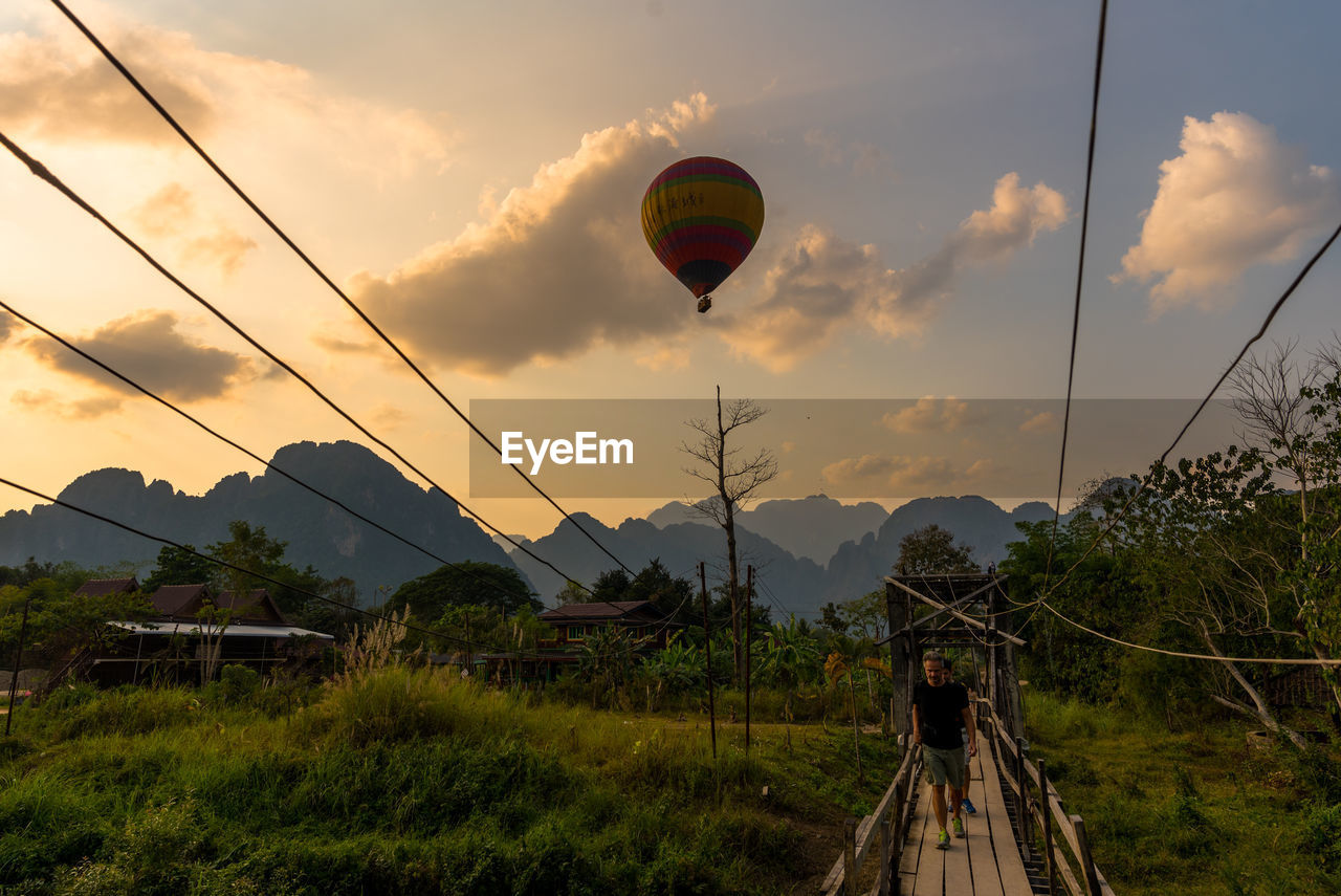 HOT AIR BALLOONS FLYING OVER TREES AGAINST SKY