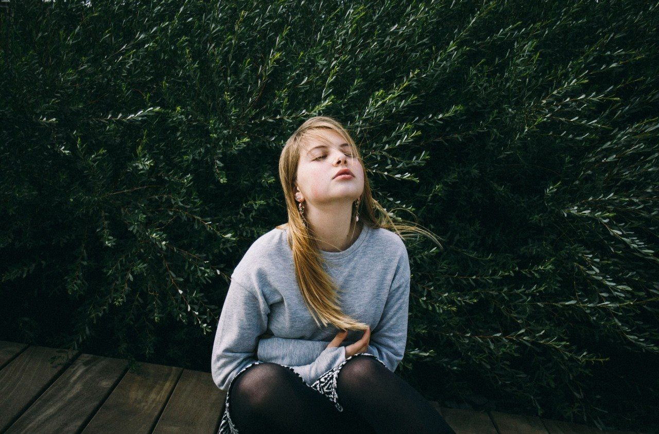 Beautiful young woman sitting with eyes closed against plants