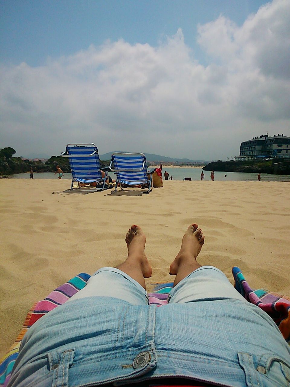 Low section of woman relaxing on beach against sky