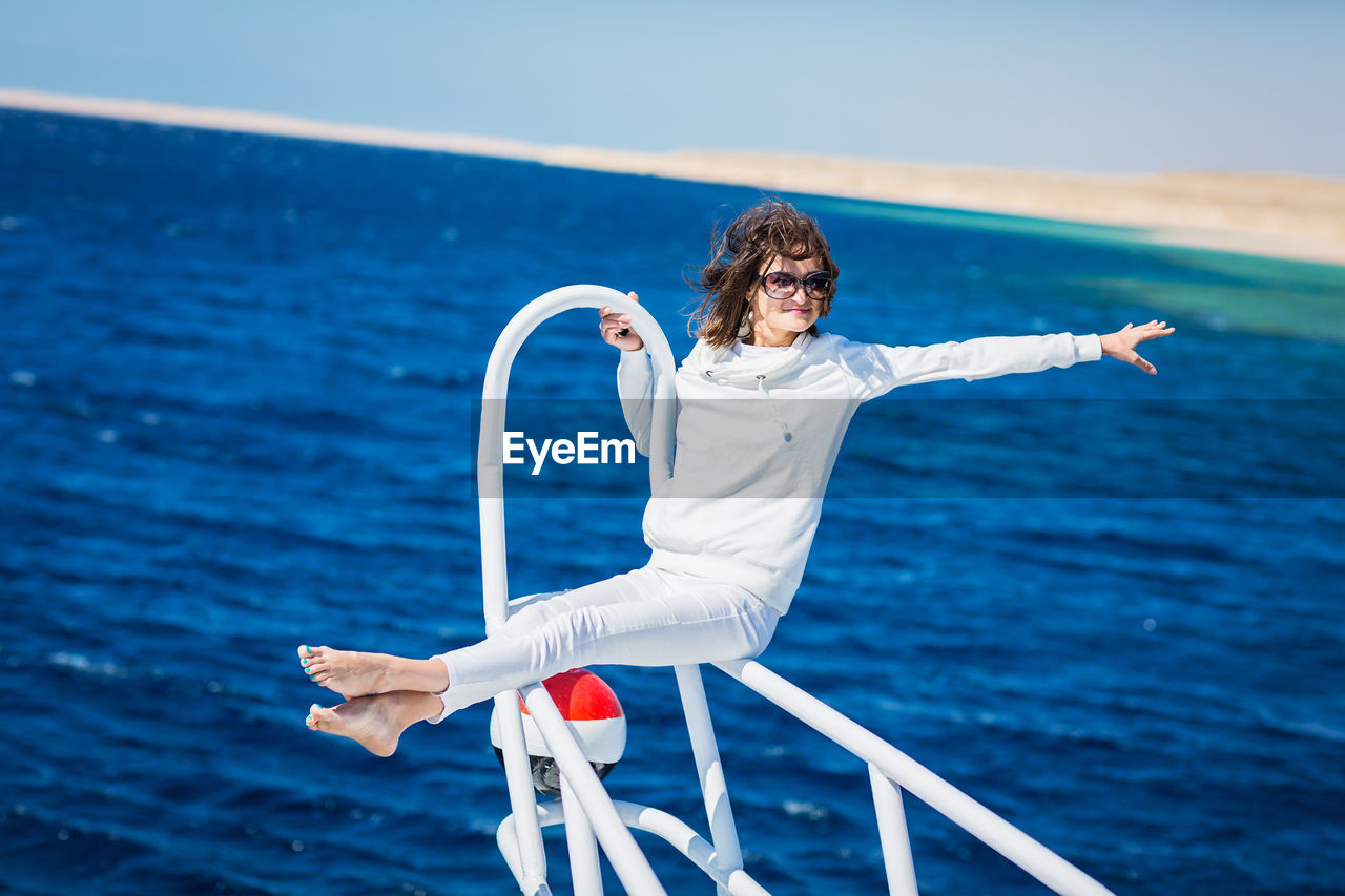 Woman relaxing on the nose of the yacht at a sunny summer day at sea