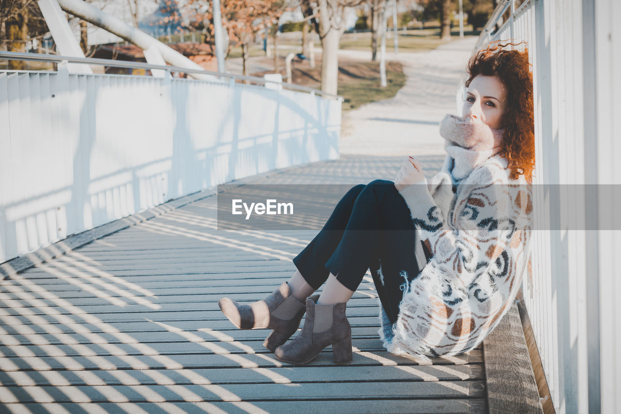 Portrait of woman sitting on footbridge