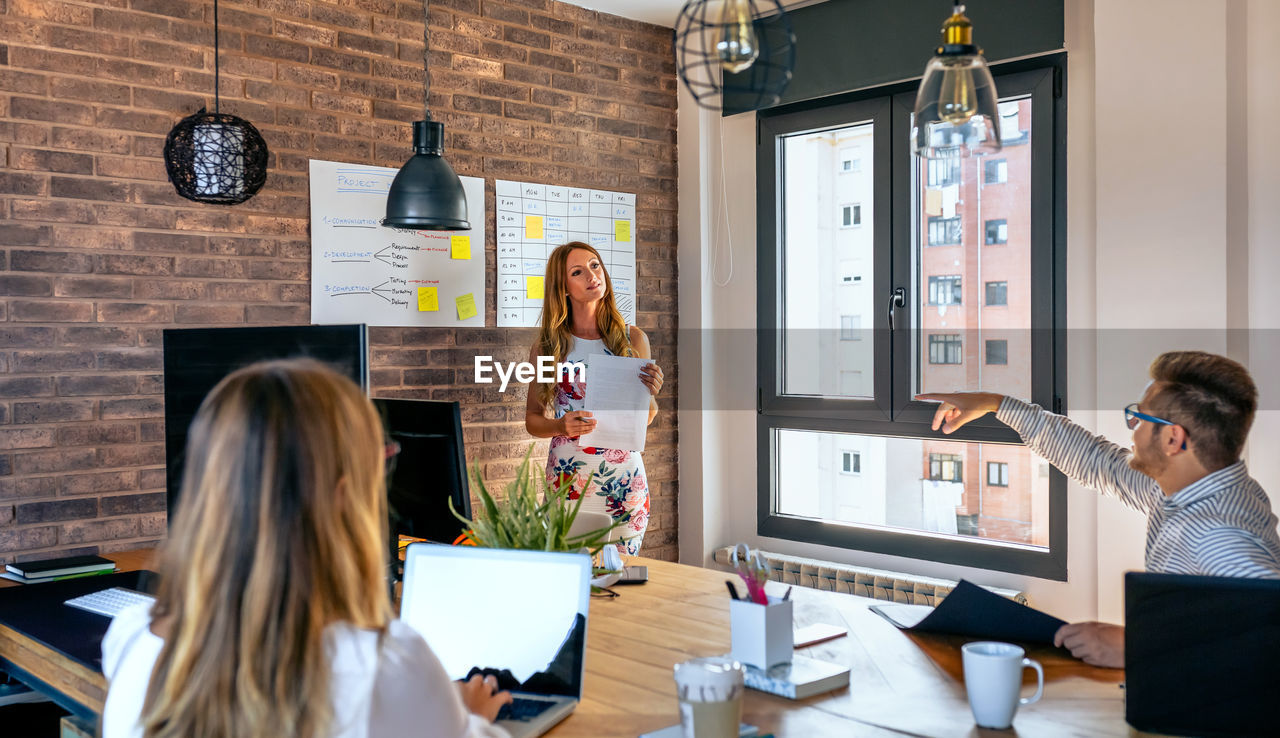 Businesswoman explaining to colleagues in meeting at office