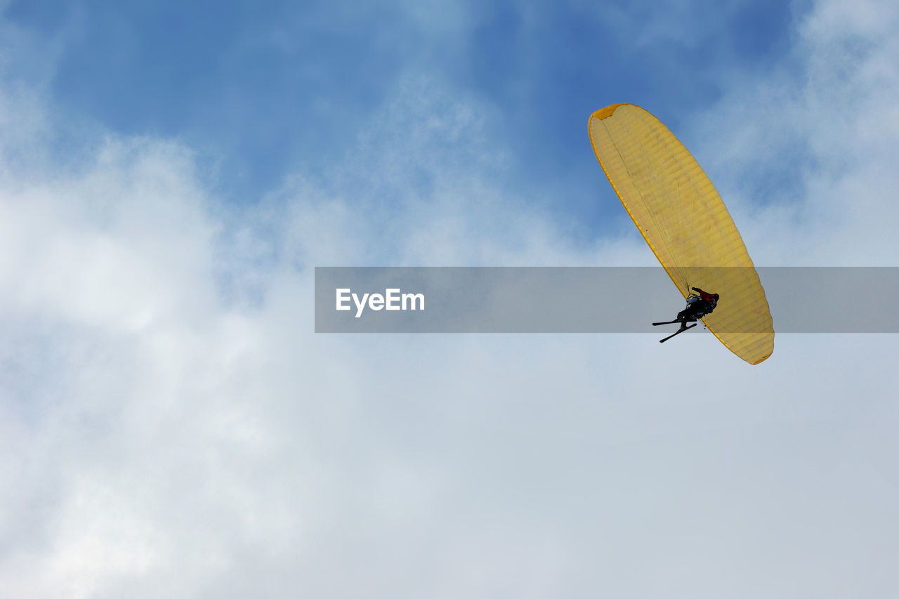 Low angle view of a yellow paraglide in cloudy blue sky with copy text space