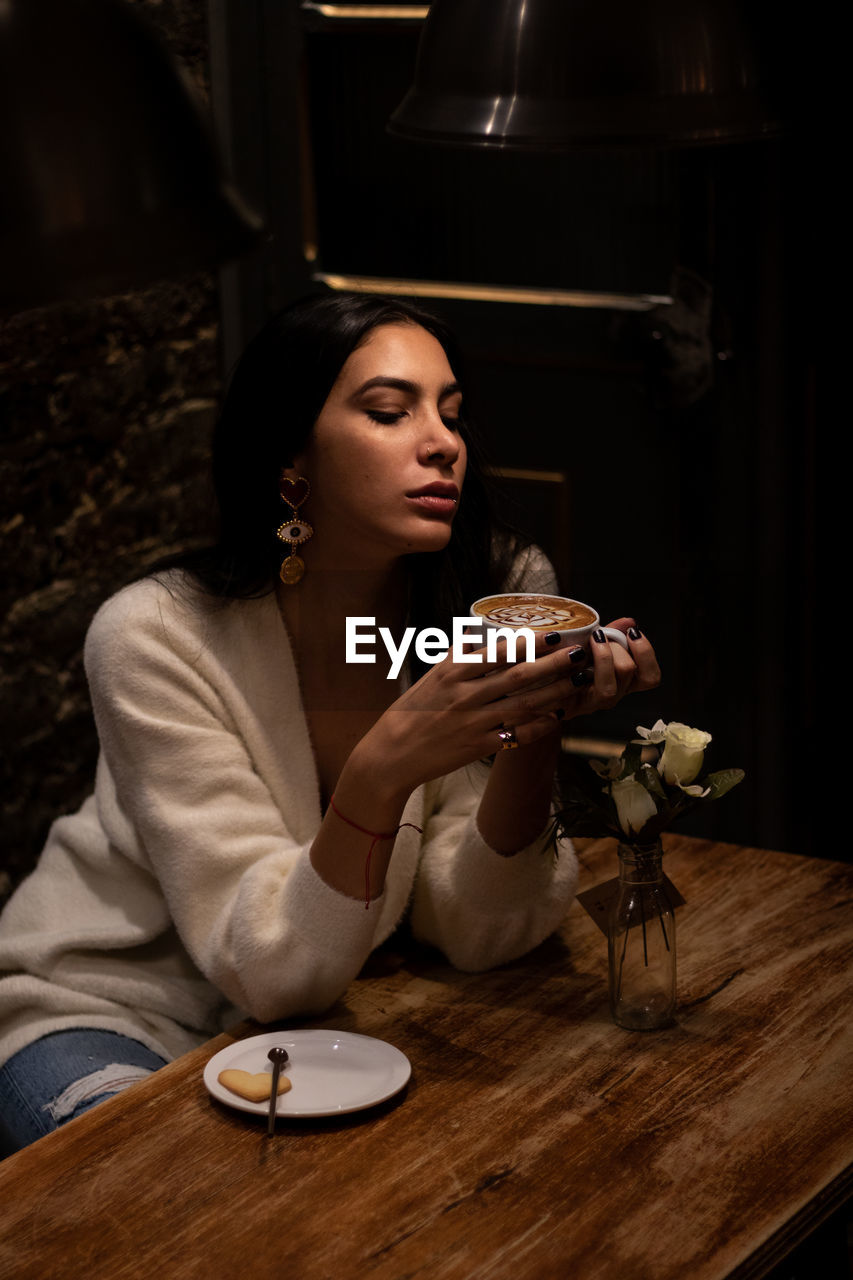 PORTRAIT OF A YOUNG WOMAN DRINKING COFFEE CUP