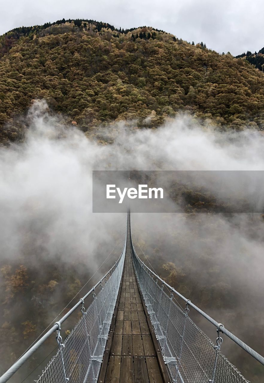 Tibetan footbridge over mountain against sky and foog