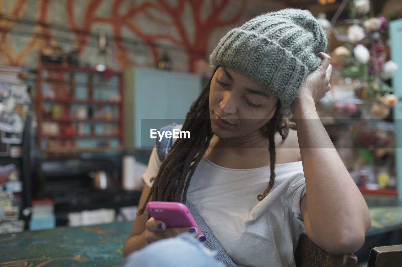 Young woman sitting in kitchen looking at her smartphone