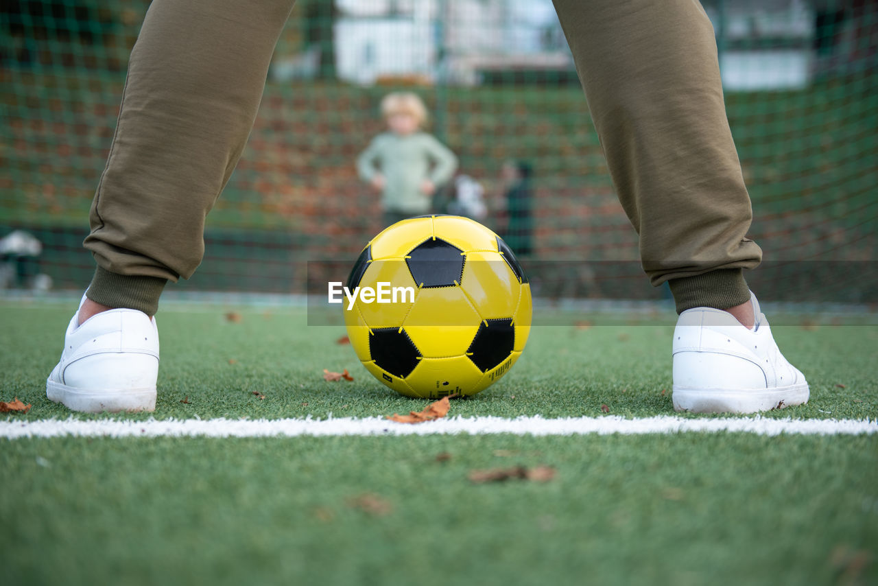 A little boy plays soccer with his father on the soccer field