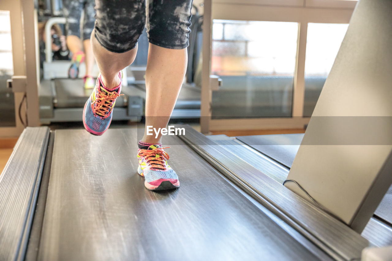 Low section of person running on treadmill in gym