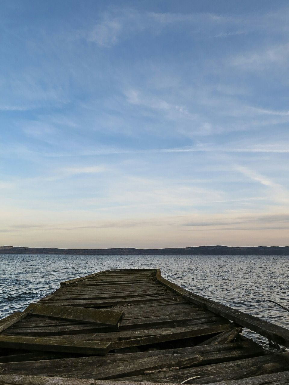 Damaged pier over lake against sky