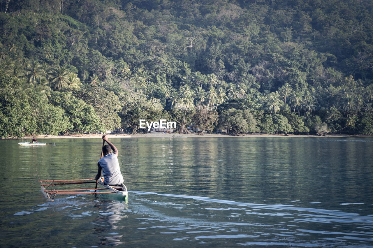 Man in boat on lake against trees