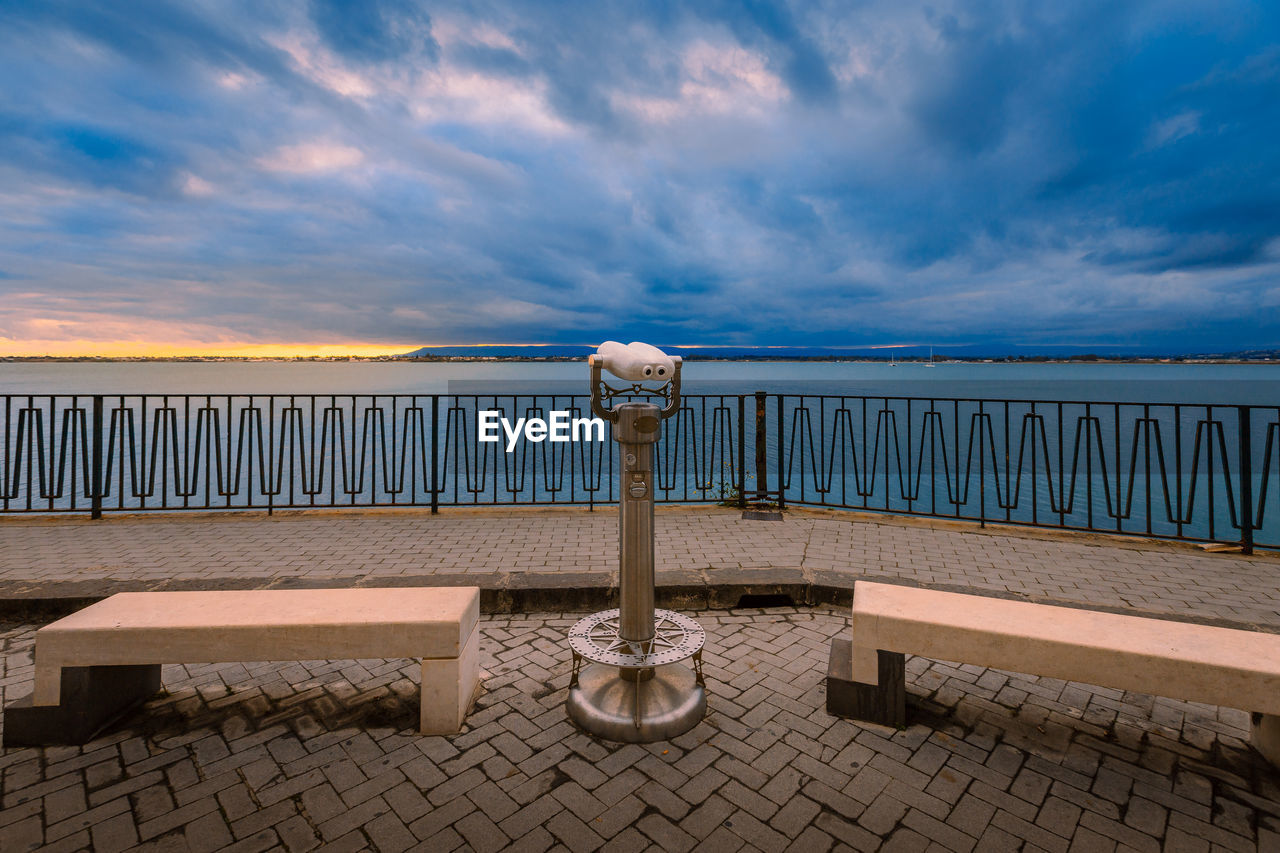 Sunset over the sea with cloudy sky with panoramic binoculars in the foreground
