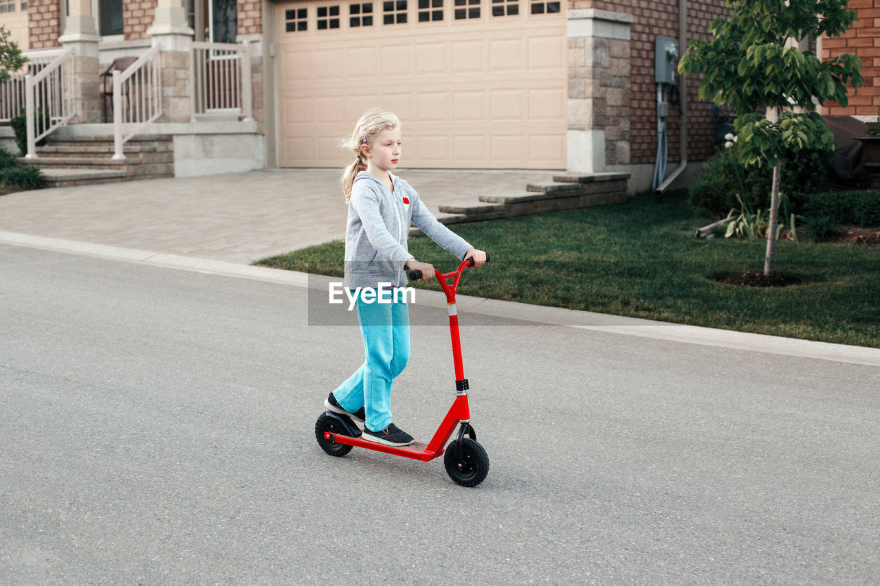 Girl riding push scooter on road