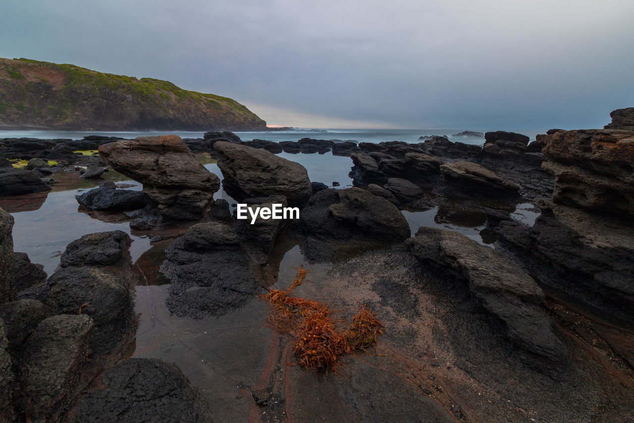 Rocks on sea shore against sky