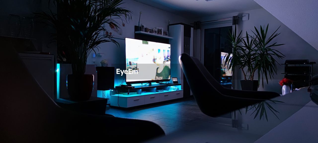 screenshot, technology, indoors, table, computer, computer equipment, furniture, night, computer monitor, plant, no people, illuminated, tree
