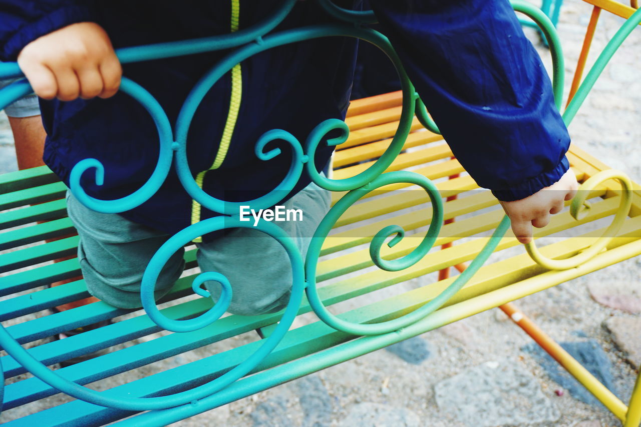 Midsection of child kneeling on bench at park