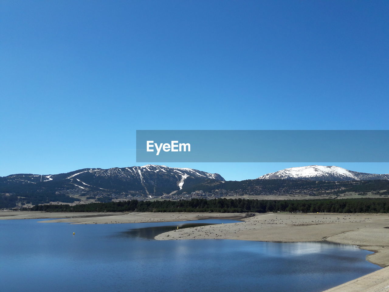 Scenic view of lake against clear blue sky