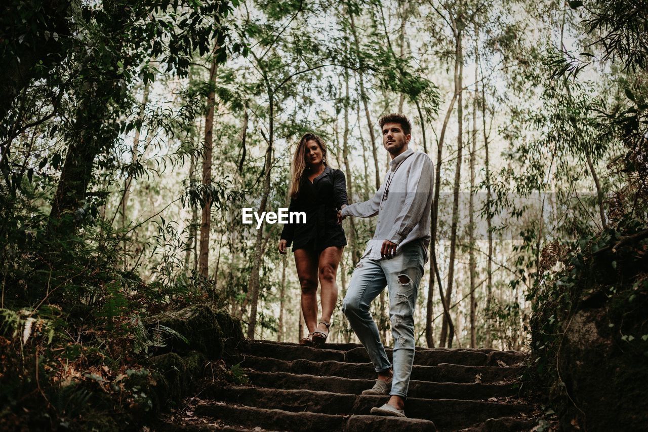 Couple walking against trees in forest