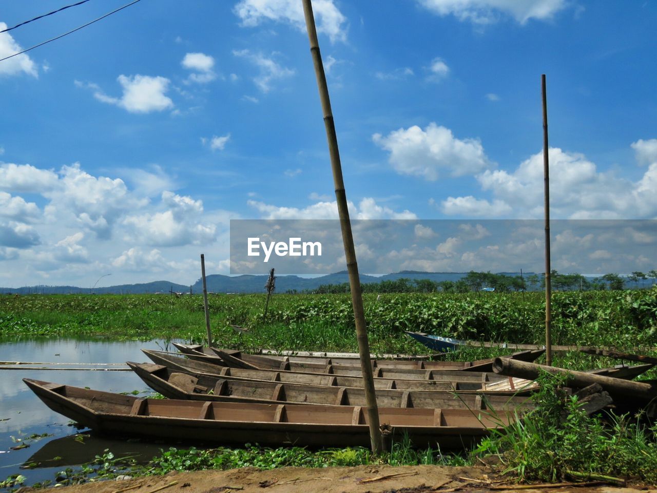 Wooden boats moored on river against sky