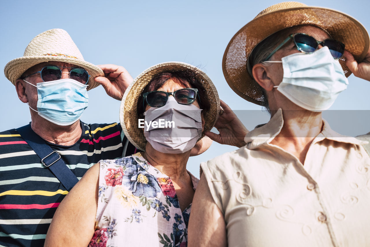 Portrait of senior people wearing hat standing against sky