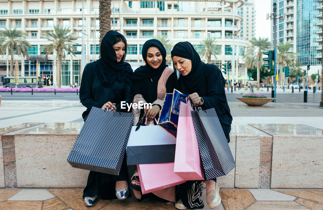 Cheerful women wearing shopping bags standing outdoors