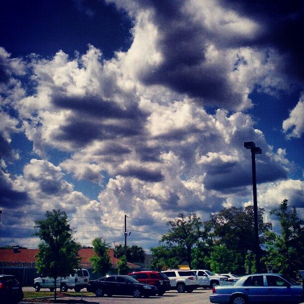 ROAD PASSING THROUGH PARKING LOT AGAINST CLOUDY SKY