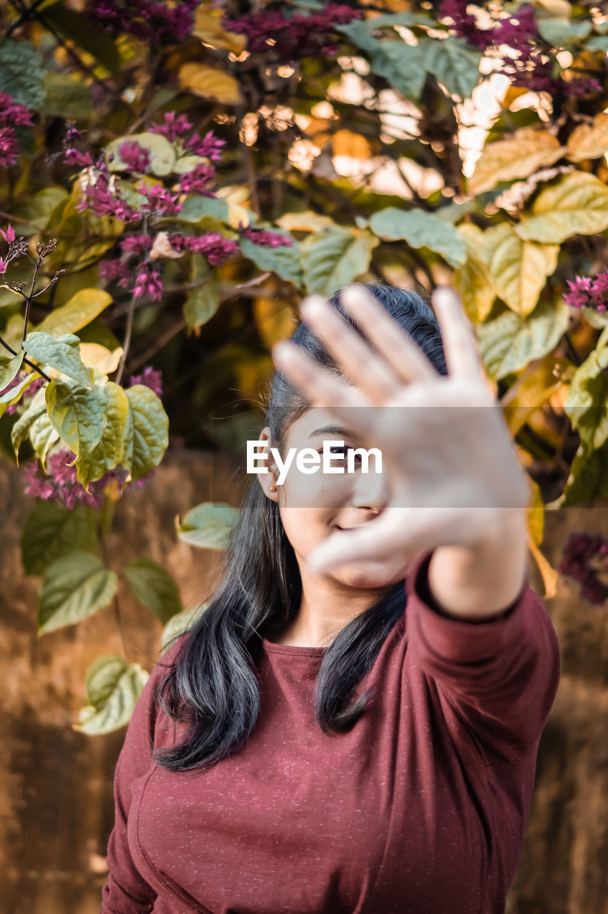 Portrait of young woman against leaves