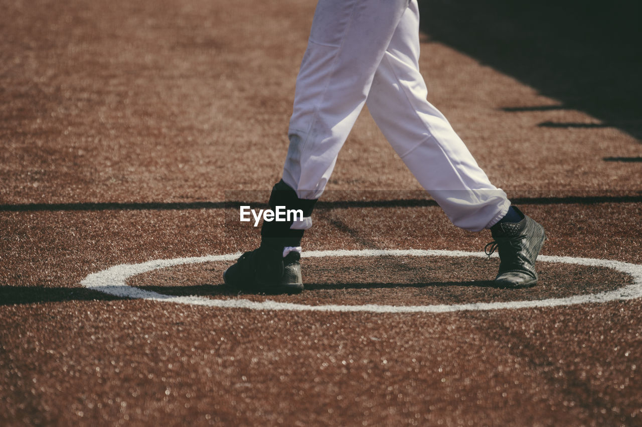 Low section of baseball player standing on playing field during sunny day