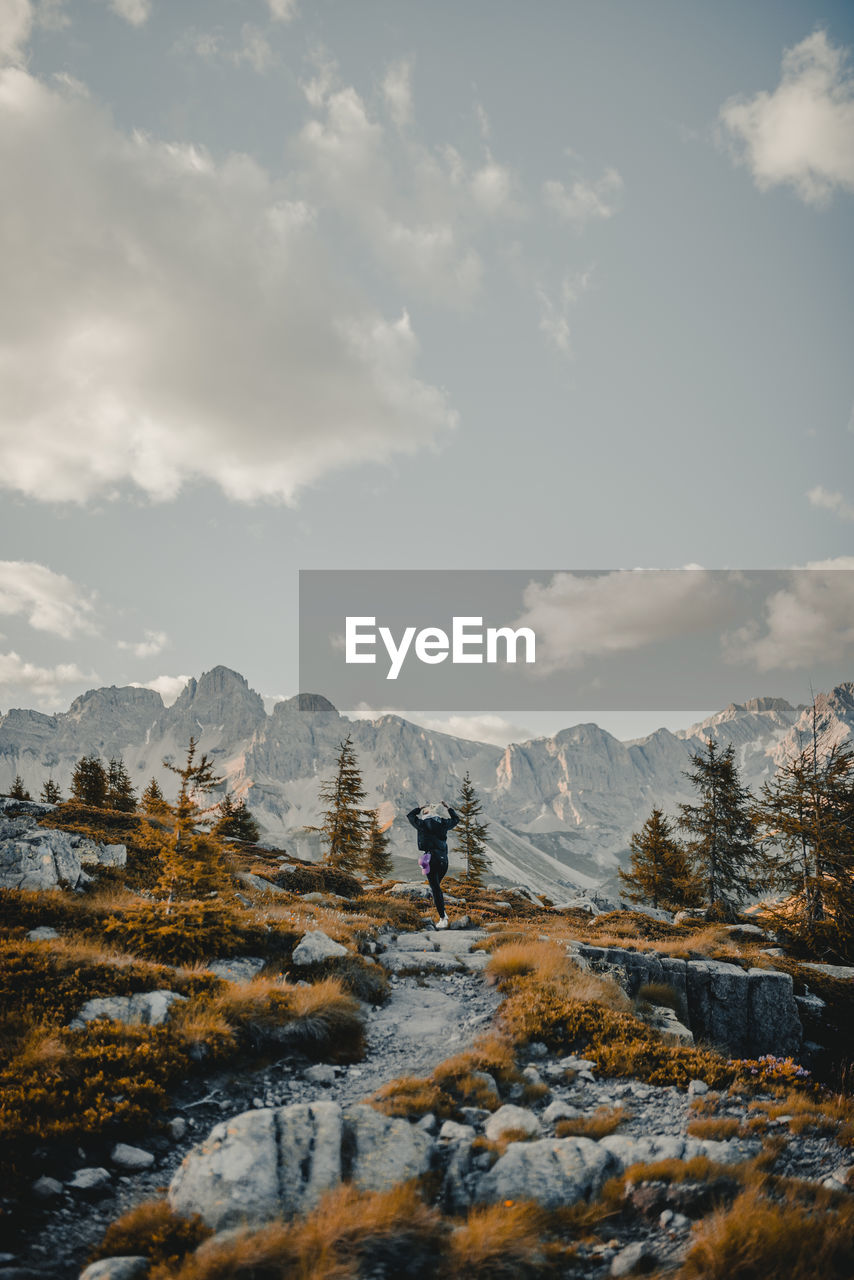 Rear view of woman dancing on mountain against sky during winter