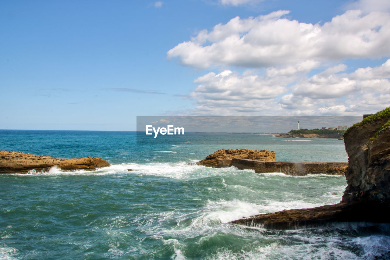 SCENIC VIEW OF ROCKY BEACH AGAINST SKY