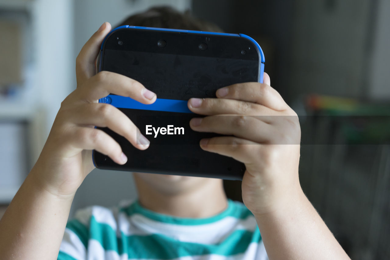 Close-up of boy holding video game in front of his face