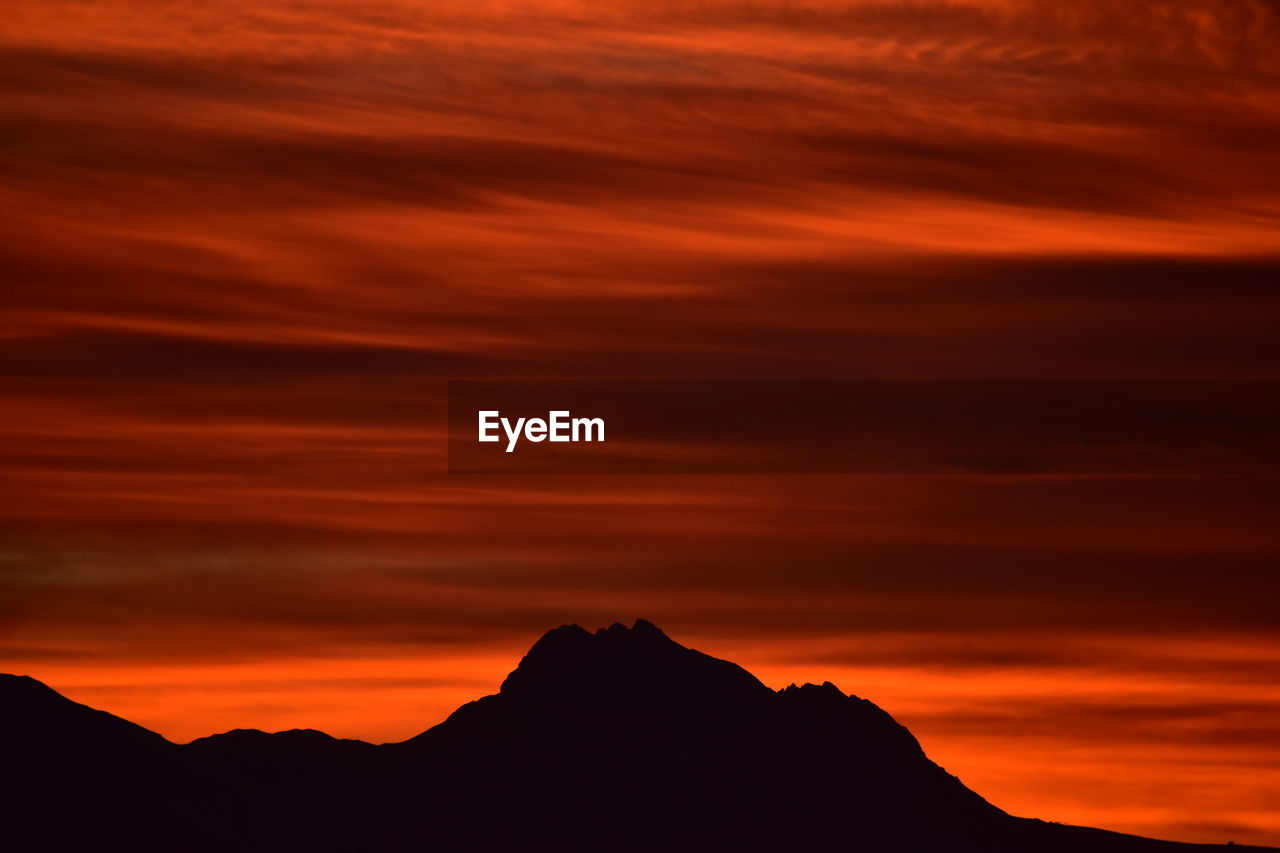 Scenic view of silhouette mountains against orange sky