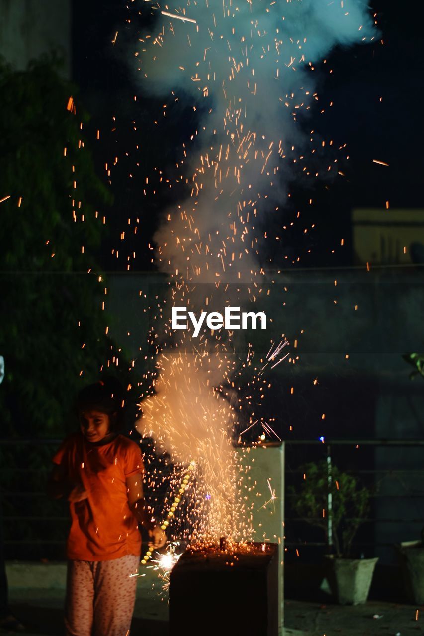 Girl standing by firework display at night