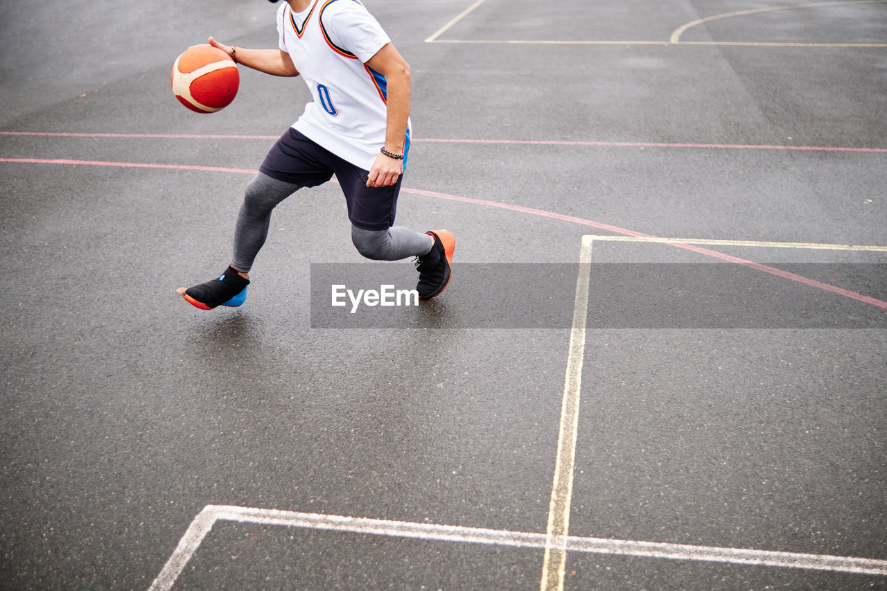 Cropped image of male playing basketball at a court outdoors. copy space.